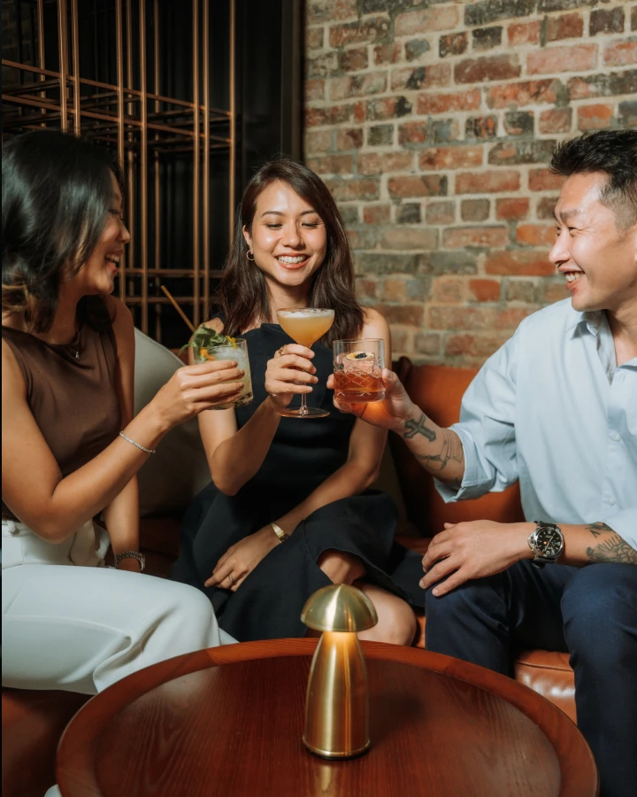 two women and a man having drinks while sitting down