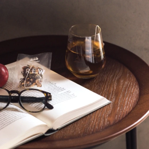 a cup of tea on a wooden table next to an opened book