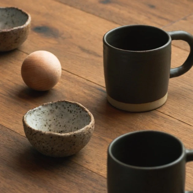 two cups and two saucepans on a wooden table