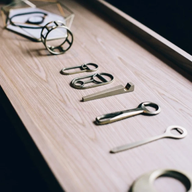 a few metallic bottle openers on a wooden tray