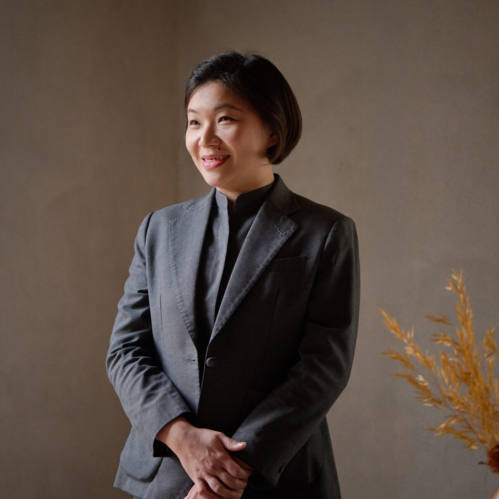 HIRES HWEE LI 750 woman with short hair wearing a blazer and smiling to the side