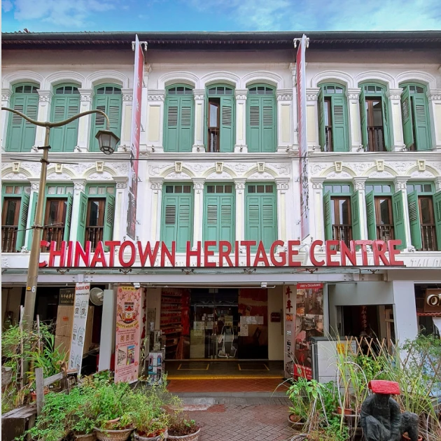 colonial style building with green window covers and large red signboard showing " chinatown heritage centre"