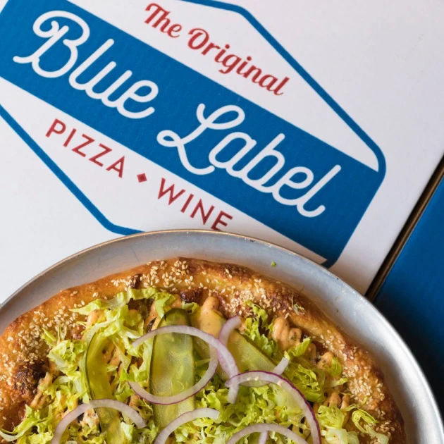 vegetarian pizza on a blue pizza box with the words "blue label pizza and wine"