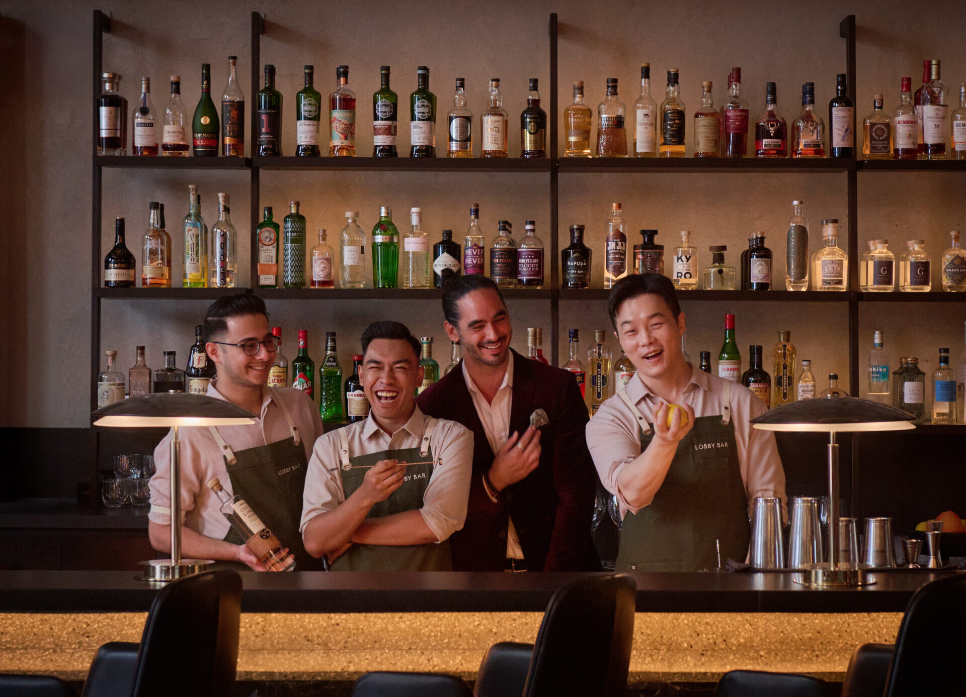 four men behind a bar counter smiling for the camera