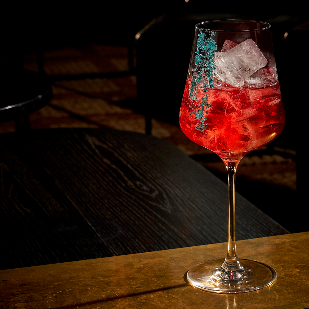 red coloured drink with ice in a glass cup